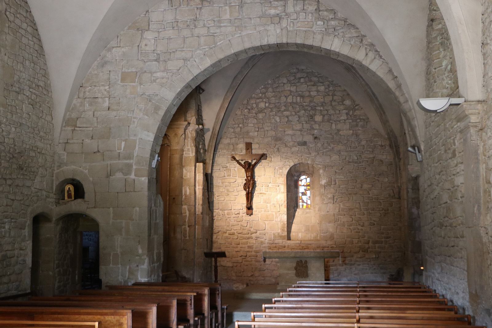 L'intérieur de l'église Sainte-Agnès, murs de pierre, voûte et crucifix de bois